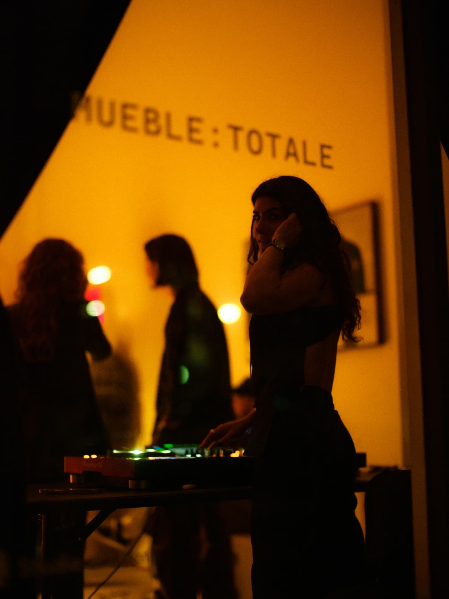 Melody.MP3 silhouetted in warm light at a Mueble:Totale party
