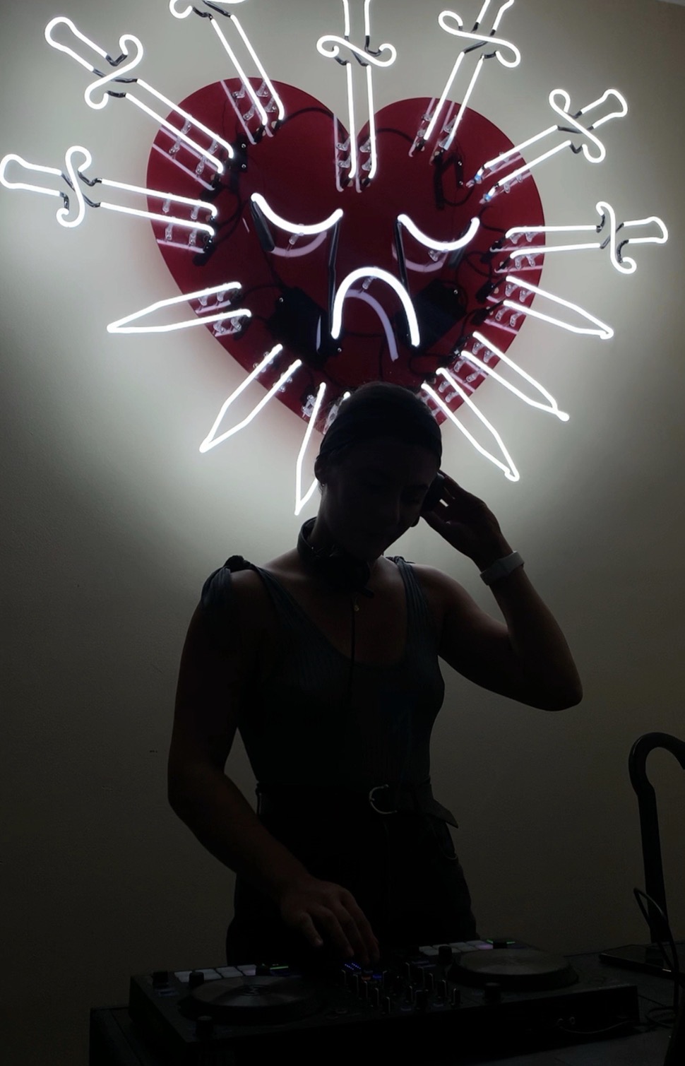 Melody.MP3 silhouetted against a neon heart sign
